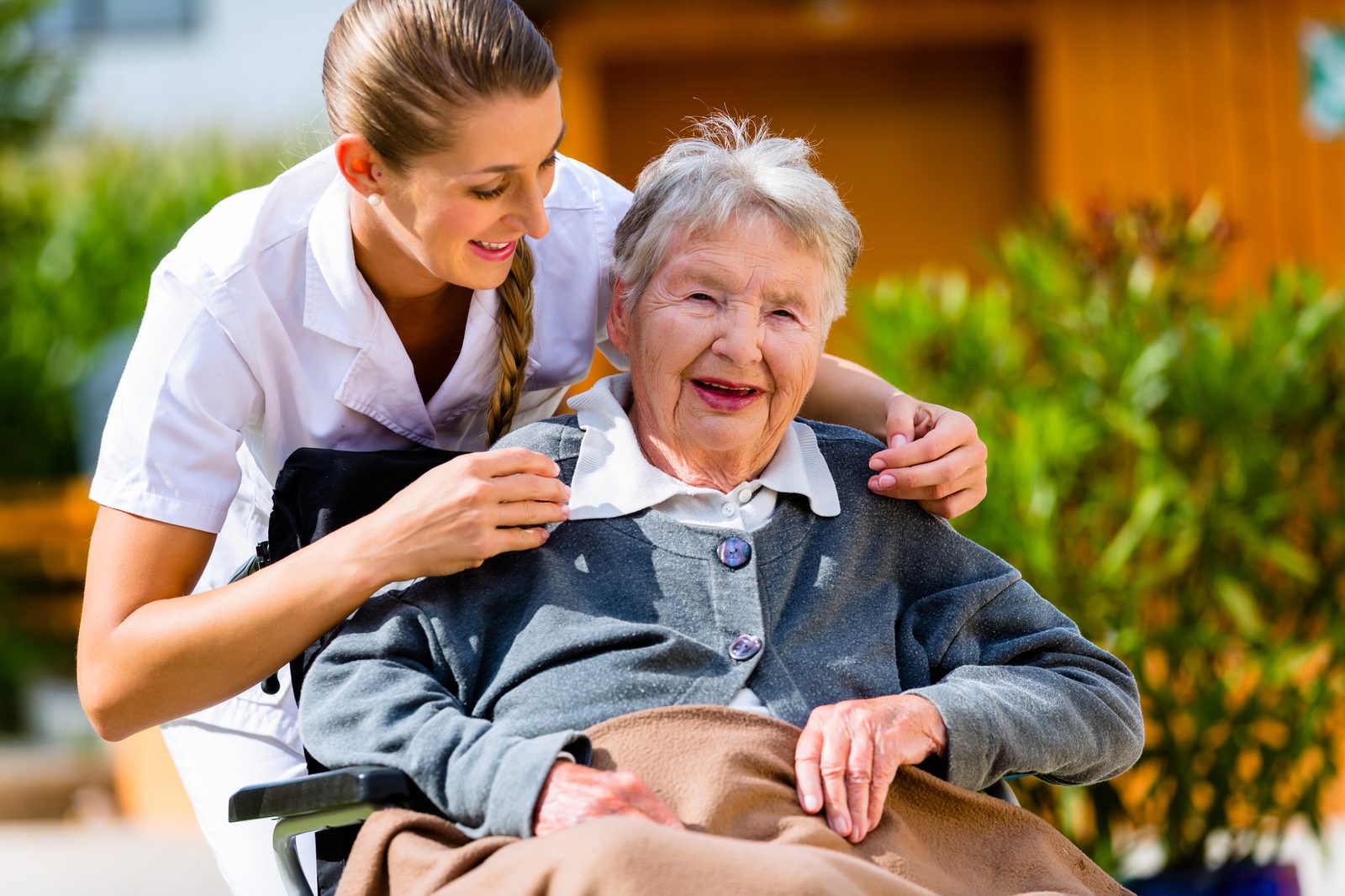 Caregiver supporting an older adult outdoors in the garden