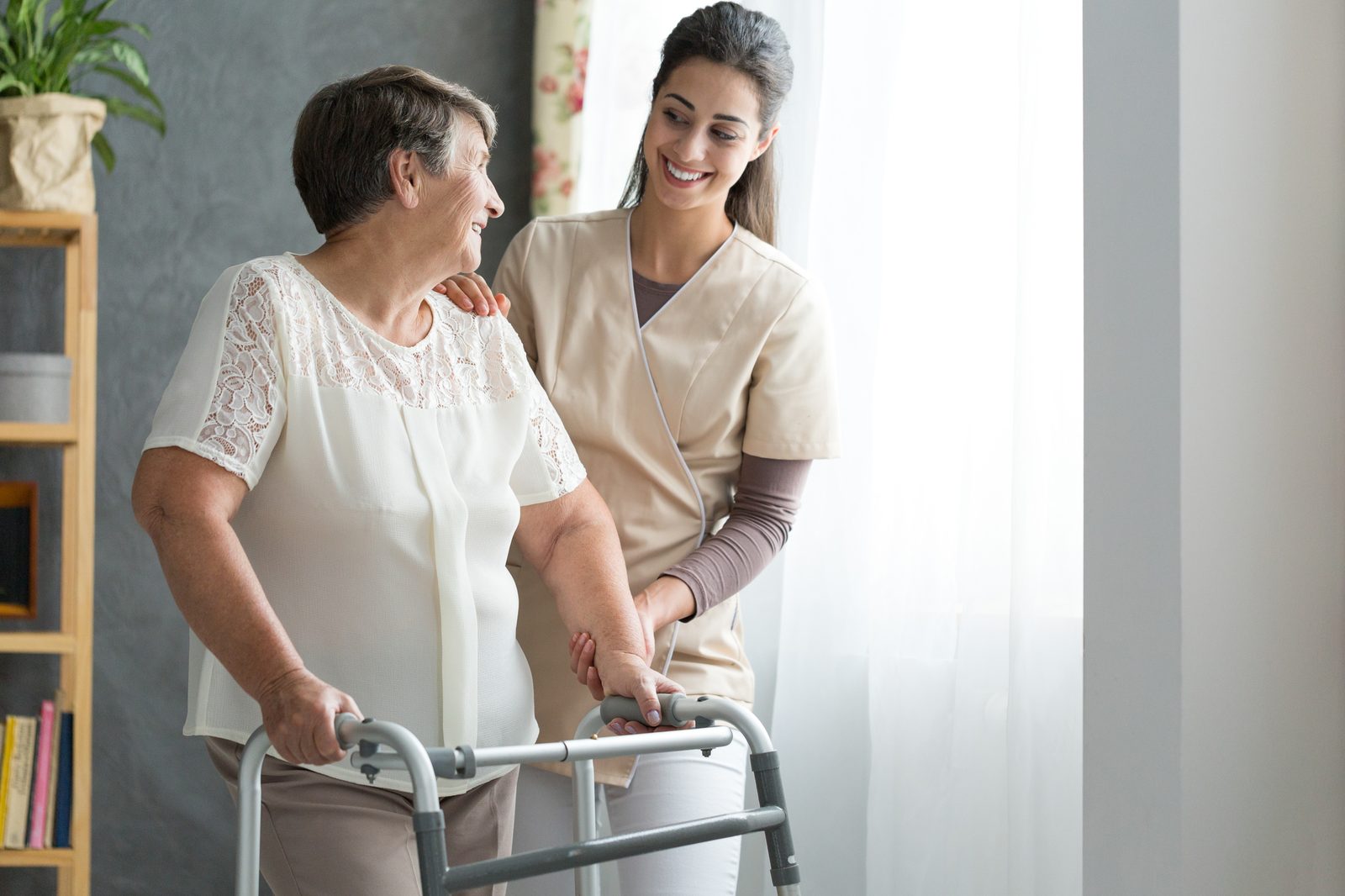 Caregiver providing light support while an older adult uses a walker at home